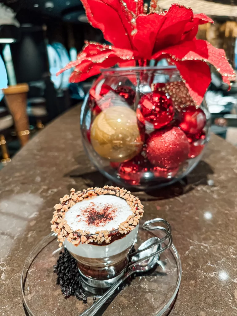 a glass cup with a dessert in it next to a bowl of christmas ornaments