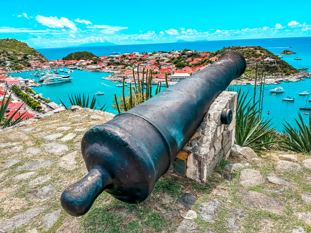 a cannon on a stone ledge with a body of water in the background